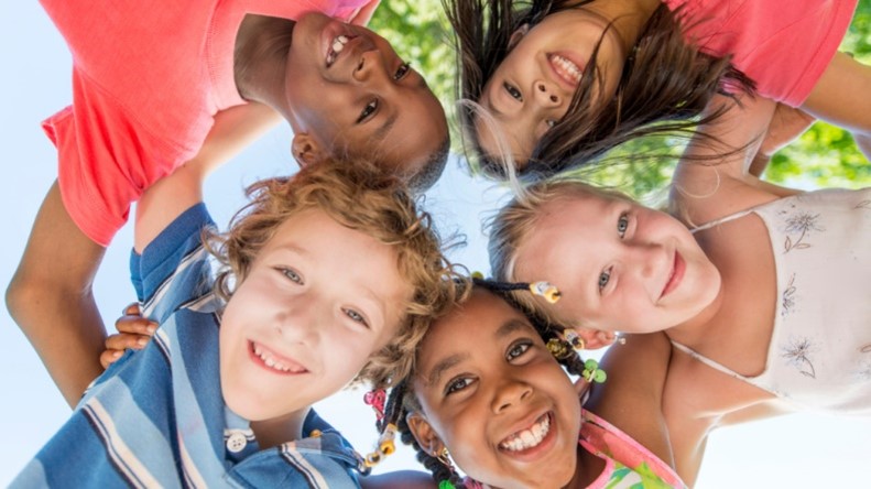 Children standing together in a circle smiling.